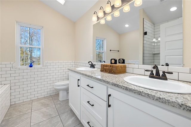 full bathroom with vaulted ceiling, tile walls, tile patterned floors, and a sink