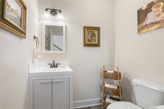 half bath with vanity, toilet, and baseboards