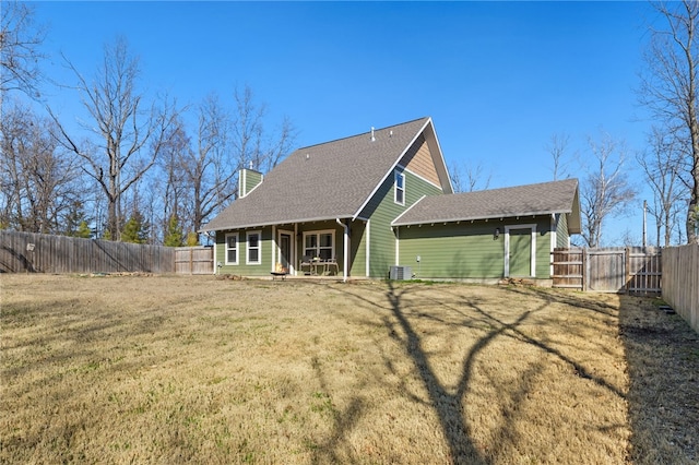 rear view of house featuring a lawn, central AC unit, a fenced backyard, and a chimney