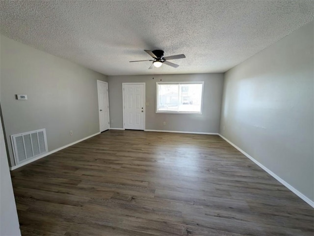 unfurnished room featuring dark wood finished floors, visible vents, and baseboards