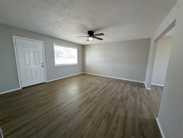 interior space featuring baseboards, dark wood-type flooring, a ceiling fan, and a textured ceiling