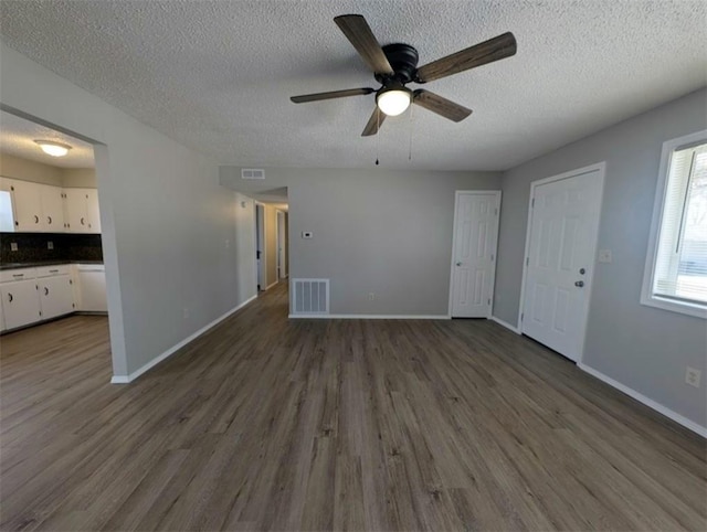 unfurnished living room featuring visible vents, baseboards, and dark wood-style flooring