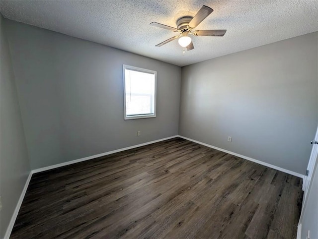 empty room with a textured ceiling, baseboards, dark wood-type flooring, and ceiling fan