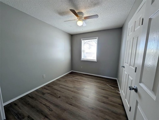 unfurnished bedroom with a ceiling fan, dark wood-style floors, baseboards, and a textured ceiling