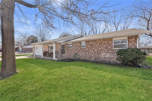 rear view of house with a yard, brick siding, and a garage