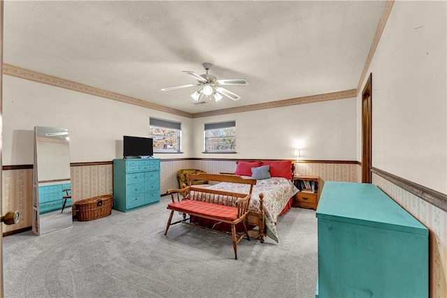 carpeted bedroom featuring a wainscoted wall, a textured ceiling, a ceiling fan, and wallpapered walls