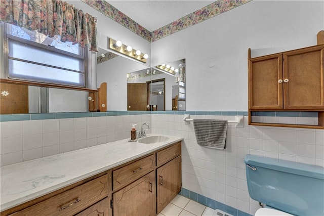 bathroom with vanity, tile patterned flooring, wainscoting, tile walls, and toilet