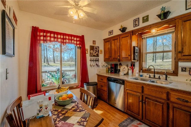 kitchen featuring light wood finished floors, dishwasher, light countertops, brown cabinets, and a sink