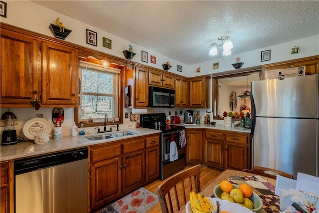 kitchen with a sink, light countertops, appliances with stainless steel finishes, a textured ceiling, and brown cabinets