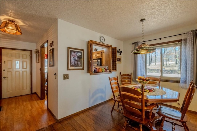 dining room with baseboards, wood-type flooring, and a textured ceiling