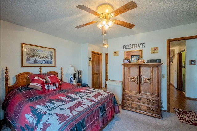 carpeted bedroom with a ceiling fan and a textured ceiling