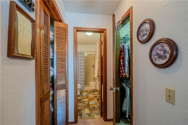 hallway with a textured wall, a textured ceiling, and carpet