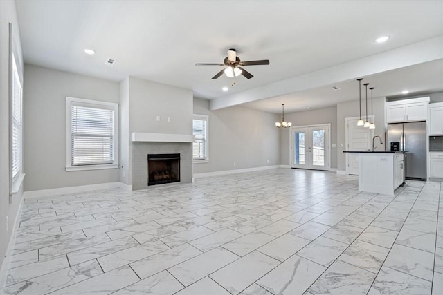 unfurnished living room with baseboards, recessed lighting, marble finish floor, and a sink