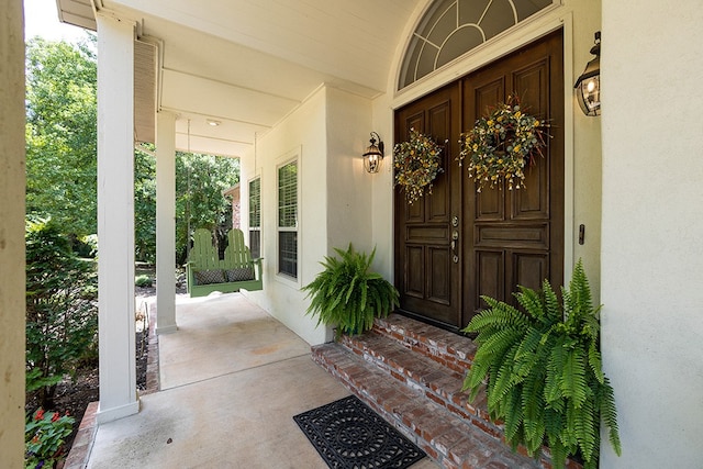 property entrance featuring covered porch and stucco siding