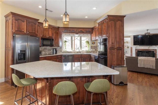 kitchen with visible vents, black appliances, light wood-style flooring, open floor plan, and decorative backsplash