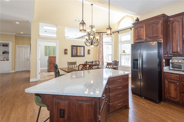 kitchen featuring wood finished floors, refrigerator with ice dispenser, a breakfast bar area, and vaulted ceiling