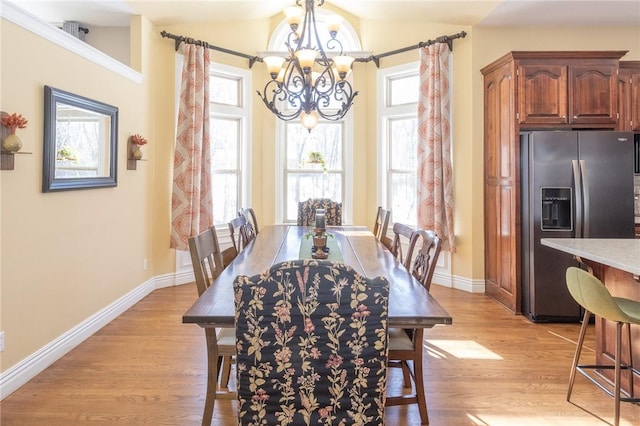 dining room with light wood finished floors, a notable chandelier, baseboards, and vaulted ceiling