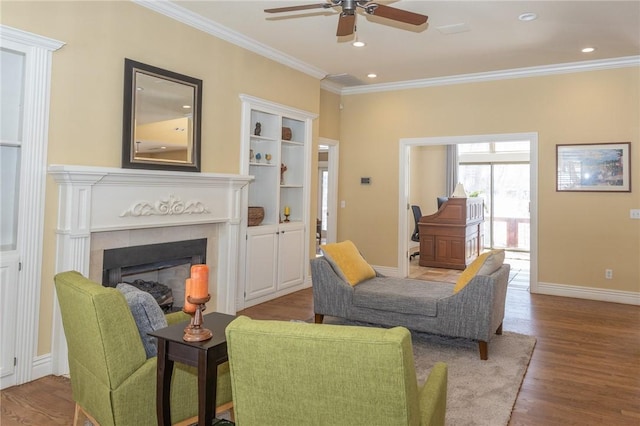 living area with baseboards, ornamental molding, recessed lighting, a fireplace, and wood finished floors