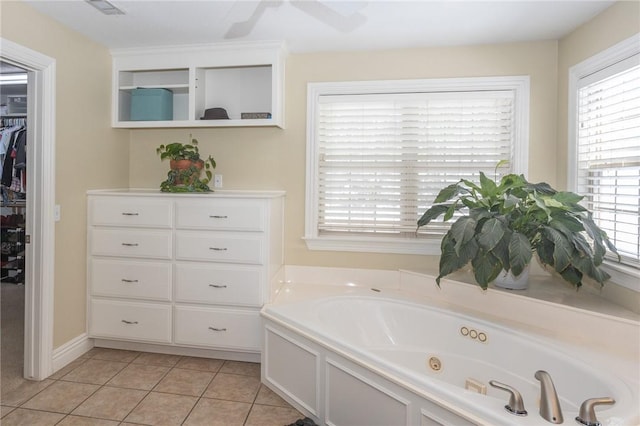 full bathroom with tile patterned flooring, a jetted tub, and a walk in closet