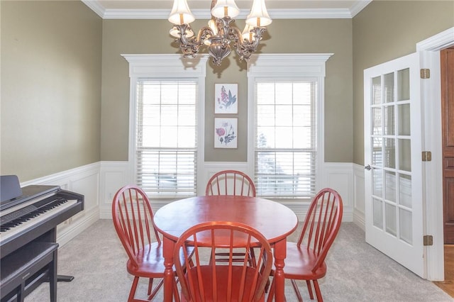 dining area with a wainscoted wall, light colored carpet, and crown molding