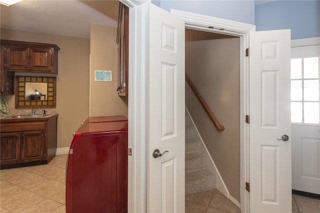 hallway with light tile patterned floors, stairway, baseboards, and a sink