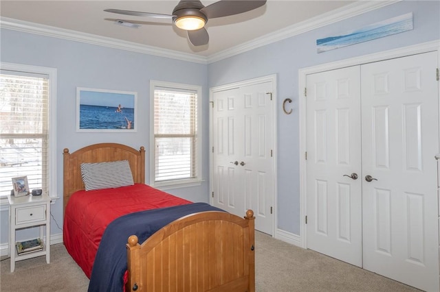 carpeted bedroom featuring visible vents, multiple closets, crown molding, baseboards, and ceiling fan