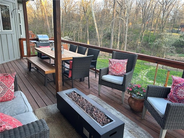 deck featuring outdoor dining space, a fire pit, and a forest view