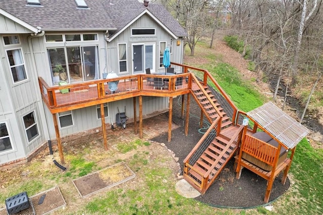 back of house featuring board and batten siding, a shingled roof, stairway, a wooden deck, and a garden