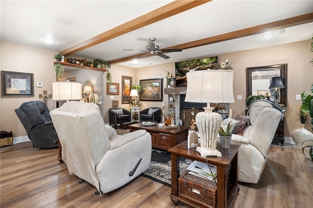 living room with beamed ceiling, baseboards, wood finished floors, and a ceiling fan