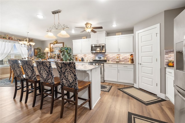 kitchen featuring a center island with sink, stainless steel appliances, a breakfast bar, and white cabinets