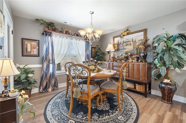 dining area featuring visible vents, baseboards, an inviting chandelier, and wood finished floors