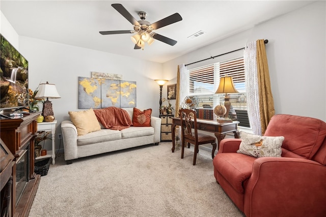 living area with carpet flooring, ceiling fan, a fireplace, and visible vents