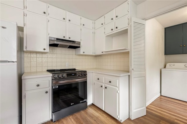 kitchen featuring under cabinet range hood, washer / clothes dryer, wood finished floors, freestanding refrigerator, and stainless steel range with electric cooktop