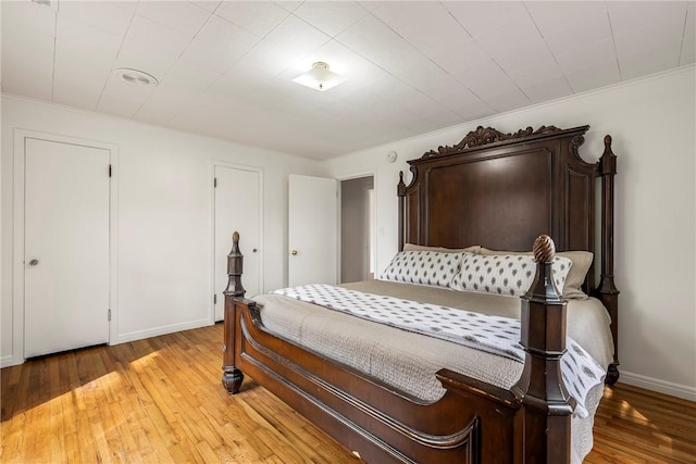 bedroom with light wood finished floors, baseboards, and ornamental molding