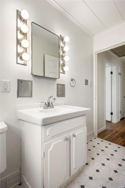 bathroom featuring toilet, vanity, baseboards, and ornamental molding