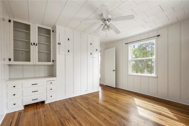 interior space with a decorative wall, wood-type flooring, and ceiling fan