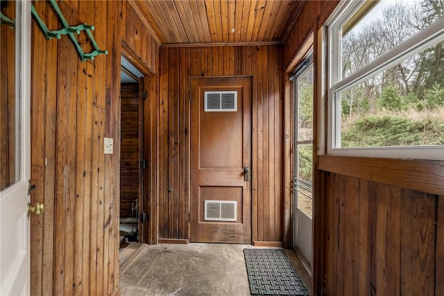 doorway with visible vents, wooden walls, and wood ceiling