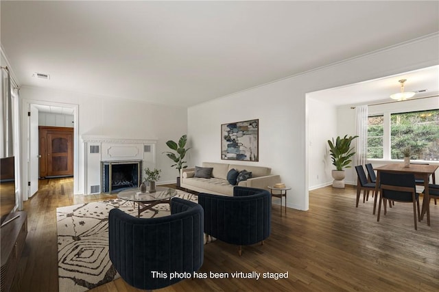 living area with a fireplace, wood finished floors, visible vents, and baseboards