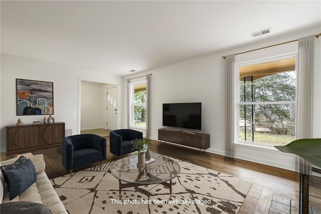 living room with plenty of natural light, wood finished floors, visible vents, and baseboards