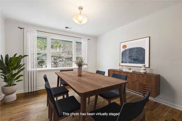 dining room with baseboards, wood finished floors, visible vents, and ornamental molding