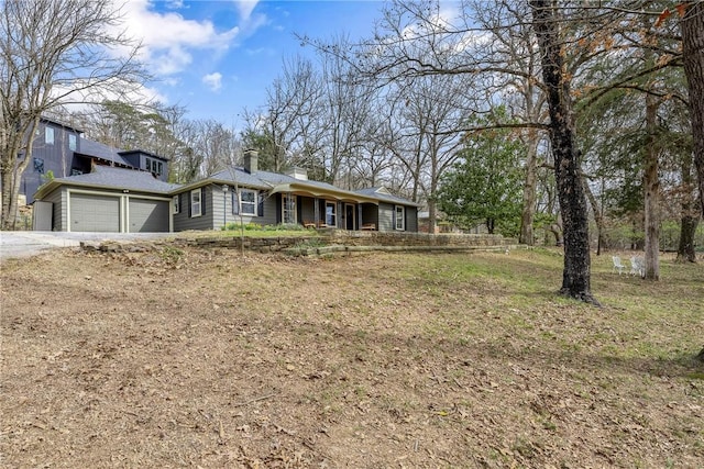 view of front of house featuring a garage, driveway, and a chimney