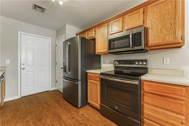 kitchen featuring dark wood-style floors, baseboards, visible vents, stainless steel appliances, and light countertops