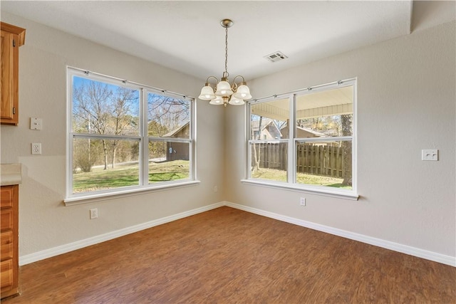 unfurnished dining area with an inviting chandelier, wood finished floors, and baseboards