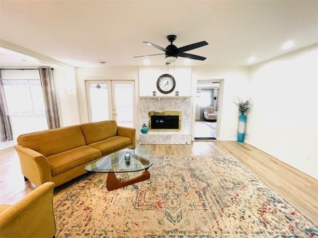 living area featuring a high end fireplace, wood finished floors, a wealth of natural light, and ceiling fan