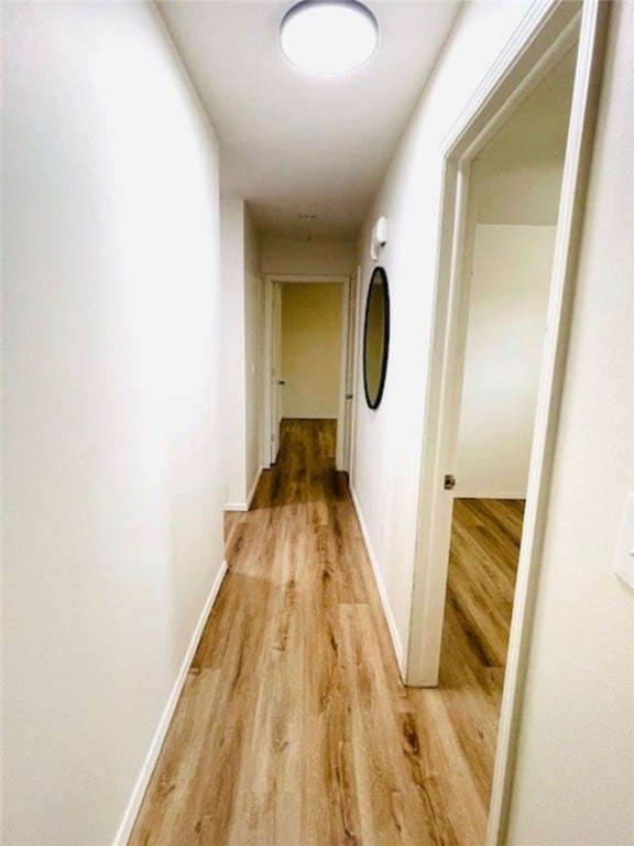 corridor featuring baseboards and light wood-style floors