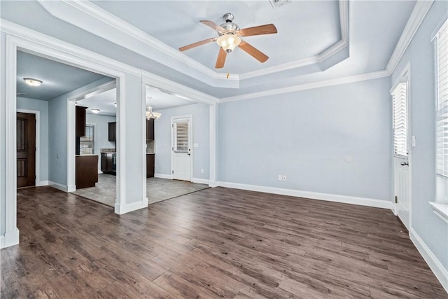 interior space featuring baseboards, a tray ceiling, dark wood-style flooring, ornamental molding, and ceiling fan with notable chandelier