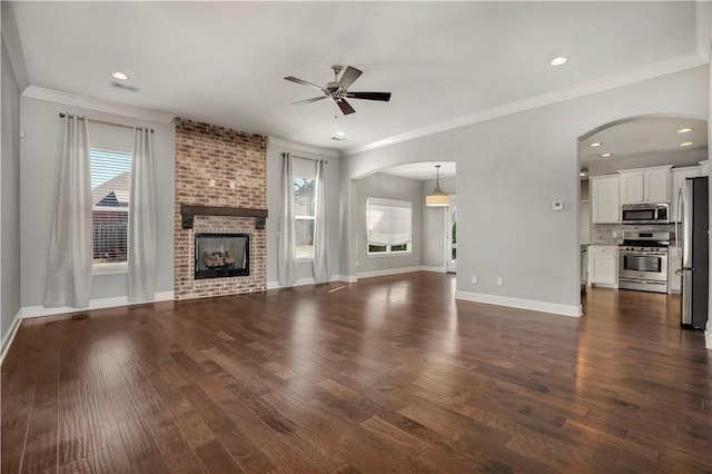 unfurnished living room featuring dark wood-type flooring, a fireplace, and arched walkways