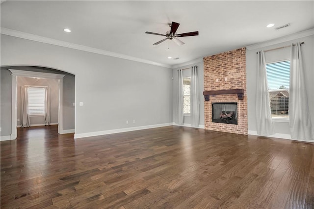 unfurnished living room with visible vents, arched walkways, dark wood-type flooring, and a healthy amount of sunlight