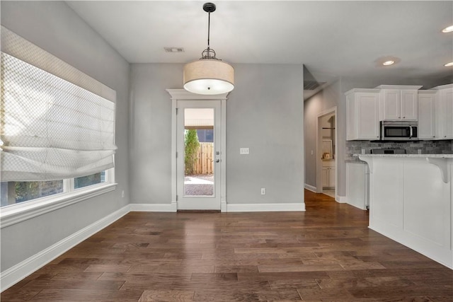 kitchen with visible vents, stainless steel microwave, tasteful backsplash, white cabinets, and dark wood-style flooring