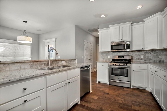 kitchen with dark wood-type flooring, decorative backsplash, appliances with stainless steel finishes, white cabinets, and a sink